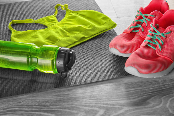 Коврик для йоги с бутылкой воды, спортивной одеждой и кроссовками на деревянном фоне
 - Фото, изображение