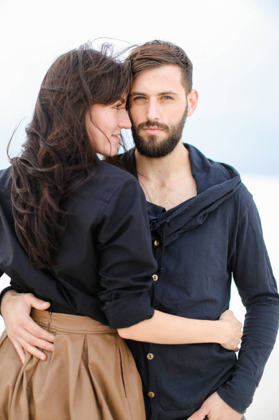 Joven pareja caucásica abrazándose y vistiendo ropa de moda en blanco monótono fondo de invierno
. - Foto, Imagen