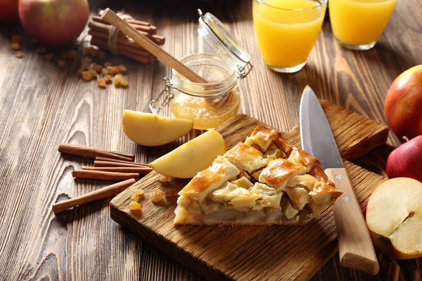 Деревянная доска с кусочком вкусного домашнего яблочного пирога на столе
 - Фото, изображение