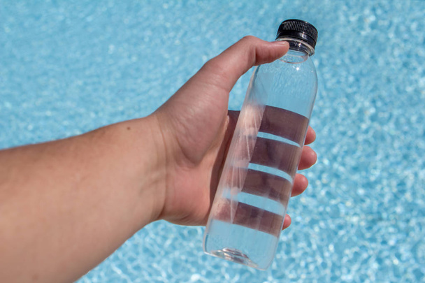 Flasche mit Wasser in der Hand auf dem Hintergrund des Meeres - Foto, Bild