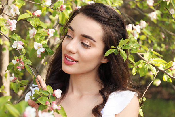 Hermosa mujer joven cerca del árbol en flor en el soleado día de primavera
 - Foto, Imagen