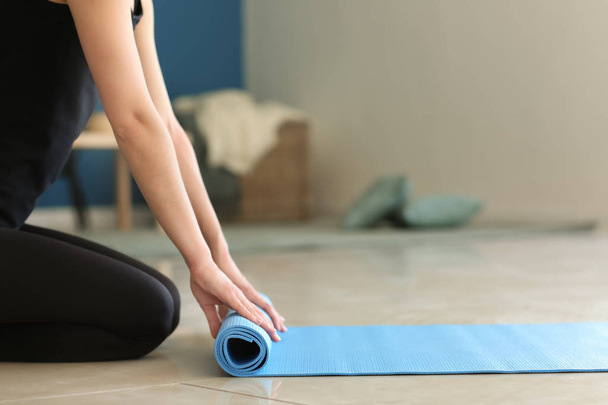 junge Frau mit Yogamatte drinnen - Foto, Bild