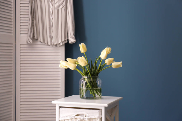美しいチューリップ色の壁にテーブルの上の花瓶 - 写真・画像