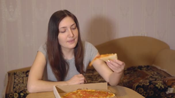 Μελαχρινή γυναίκα τρώει νόστιμο πίτσα στο σπίτι - Πλάνα, βίντεο