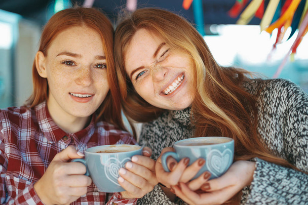 Улыбающиеся красивые молодые женщины, позирующие с кофе
 - Фото, изображение
