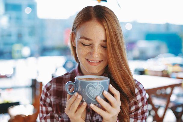 コーヒーの大きなカップを楽しんでいる自然な赤みを帯びた少女のクローズ アップ - 写真・画像