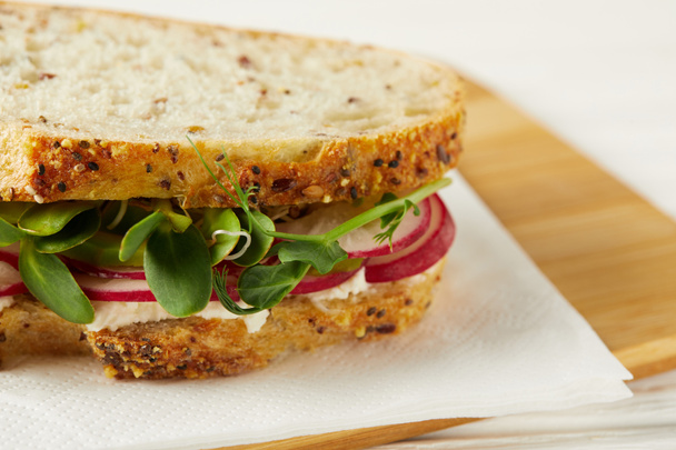 close-up shot of fresh sandwich with radish slices and pea shoots on wooden cutting board - Foto, Imagem