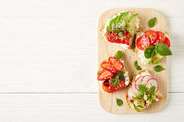 top view of fresh sandwiches on cutting board on white wooden surface - Photo, Image