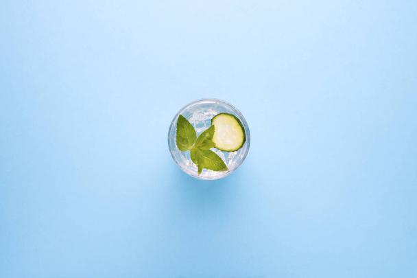Refreshing drink with ice, mint and cucumber on a blue background. The concept of quenching thirst in the summer. Flat lay, top view. - Fotó, kép