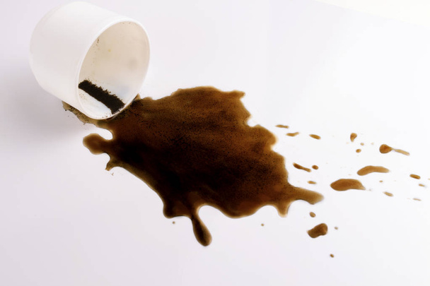 White cup and spilled black coffee on a white background. - Photo, Image