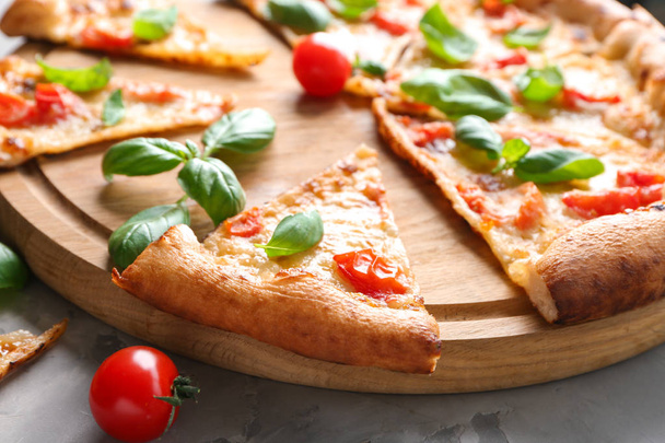 Junta con rebanadas de deliciosa pizza Margherita en la mesa, primer plano
 - Foto, imagen