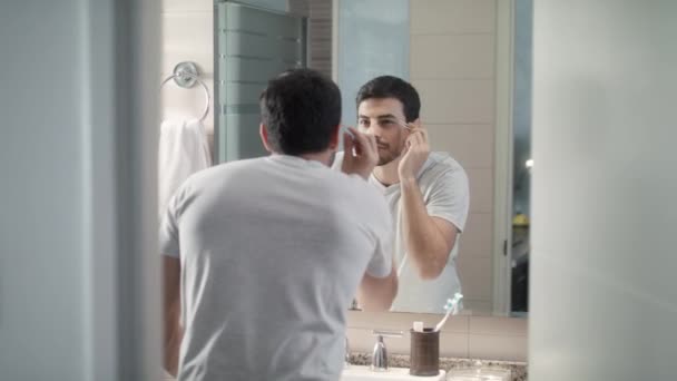Komea mies, jolla on parran hoito kylpyhuoneessa kotona aamurutiinia ja kehon hoitoa varten. Valkoihoinen metroseksuaali henkilö leikkaamalla kulmakarvat pinseteillä
 - Materiaali, video