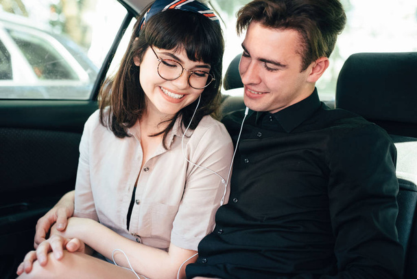 美しい男を抱いて、女の子と車の上に座って、笑顔. - 写真・画像