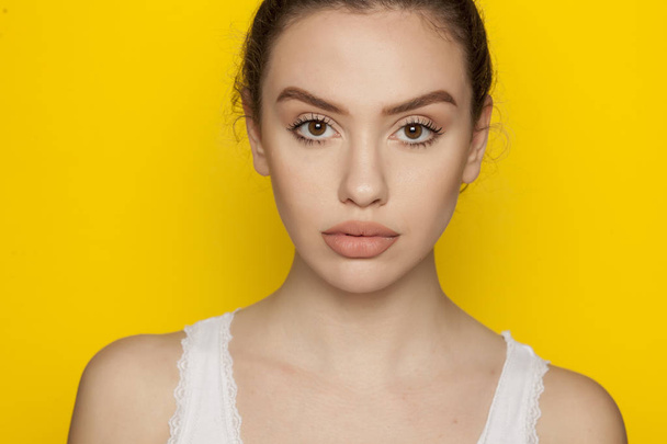 Beautiful young woman posing on a yellow background - Photo, Image