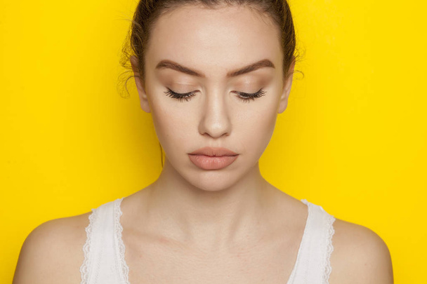 Beautiful young woman posing on a yellow background - Photo, Image