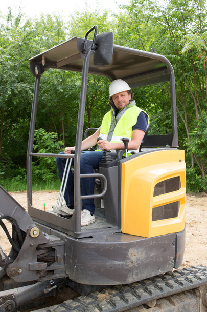 homem máquina escavadeira carregador motorista durante trabalhos de terraplanagem ao ar livre no local de construção
 - Foto, Imagem
