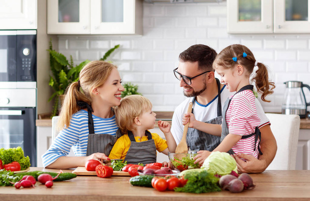 щаслива сім'я з дітьми готує овочевий салат вдома
 - Фото, зображення