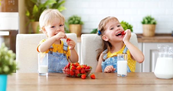 Щасливі діти дівчинка і хлопчик брат і сестра їдять полуницю з міллю
 - Фото, зображення