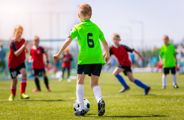 草サッカーの試合を蹴る少年。青年フットボールの試合。子供のスポーツ競争。屋外で遊ぶ子供たち - 写真・画像