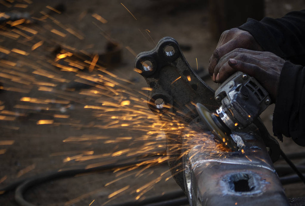 Trabalho de metal. Homem retifica uma peça de aço com um moedor de ângulo
 - Foto, Imagem