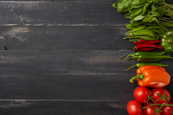 ingredients for healthy salad: basil, chili peppers, paprika, cherry tomatoes on dark wooden background with copy space - Photo, image