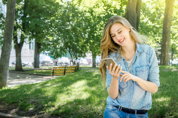 Усміхнені бізнесмени випадкова жінка тримає мобільний телефон з довгим волоссям у зеленому природному парку сонячний день фону
 - Фото, зображення