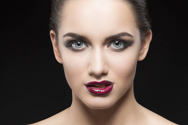 mujer joven con labios morados posando sobre fondo negro
 - Foto, Imagen