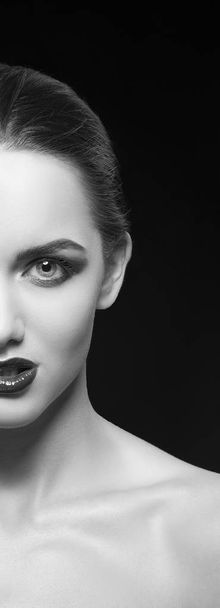 Half face of young woman with dark lips on black background - Фото, изображение