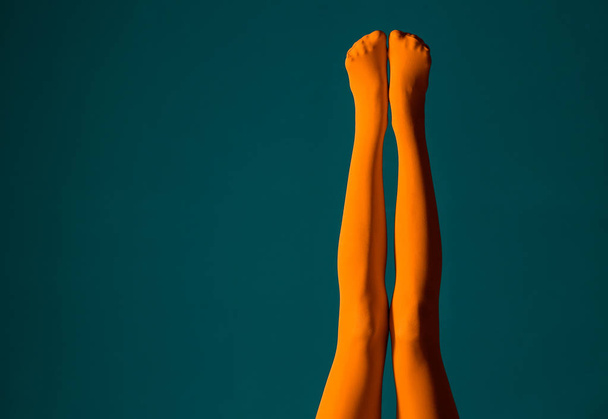 Beine der schönen jungen Frau in Strumpfhosen auf farbigem Hintergrund - Foto, Bild