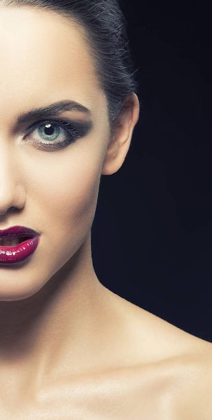 Half face of young woman with vinous lips on black background - Fotó, kép