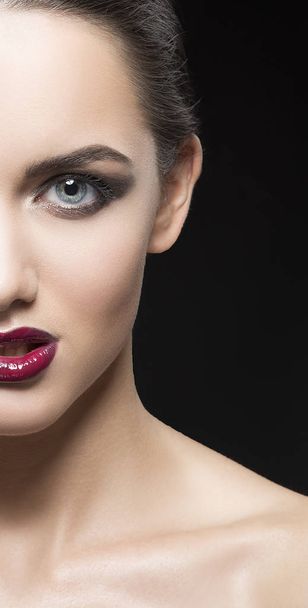 Demi-visage de jeune femme aux lèvres vineuses sur fond noir
 - Photo, image