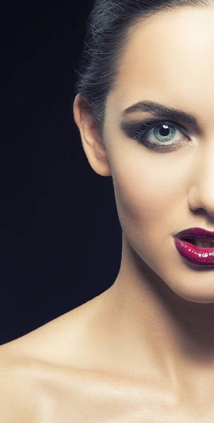 Halbgesicht einer jungen Frau mit weinerlichen Lippen auf schwarzem Hintergrund - Foto, Bild