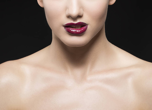 Retrato recortado de mujer joven con labios vinosos sobre fondo negro
 - Foto, Imagen