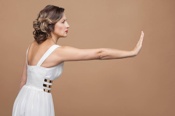 vue latérale de la femme en robe blanche montrant le panneau stop sur fond brun clair, concept d'émotion et de sentiment
 - Photo, image