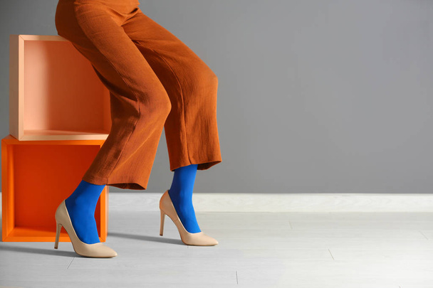 Legs of beautiful young woman in tights and trousers against color wall - 写真・画像