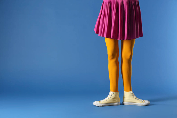 Piernas de hermosa mujer joven con mallas y falda en el fondo de color
 - Foto, imagen