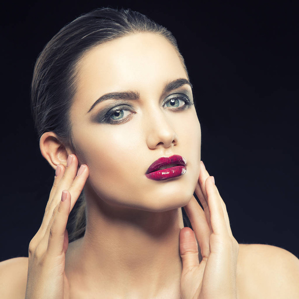 young woman with purple lips posing on black background - Foto, afbeelding