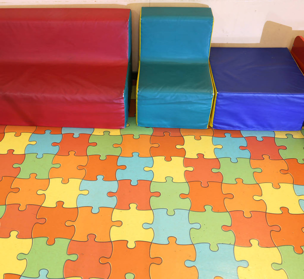 sillones pequeños para niños con una alfombra de rompecabezas de colores en un jardín de infantes
 - Foto, imagen