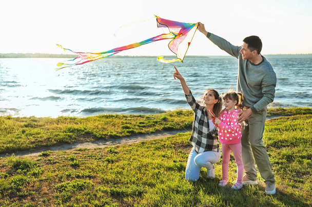 Happy family flying kite near river - Photo, Image