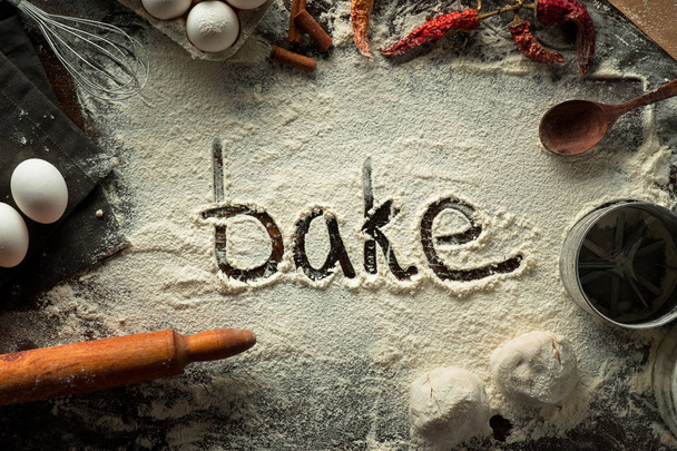 Word Bake on cooking background with flour on the table - Foto, Bild