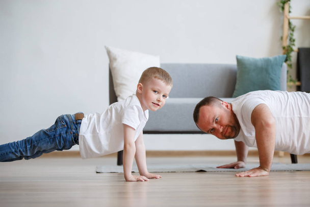 Image of happy dad and son pushing on floor - Foto, Imagen