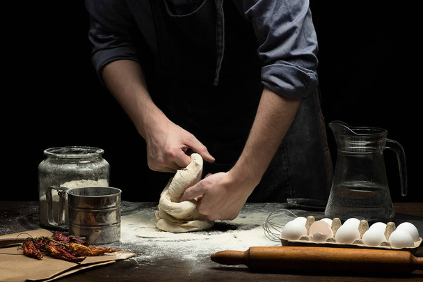 Hands are kneading the dough on wooden table - Φωτογραφία, εικόνα