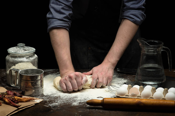 Hands are kneading the dough on wooden table - Φωτογραφία, εικόνα