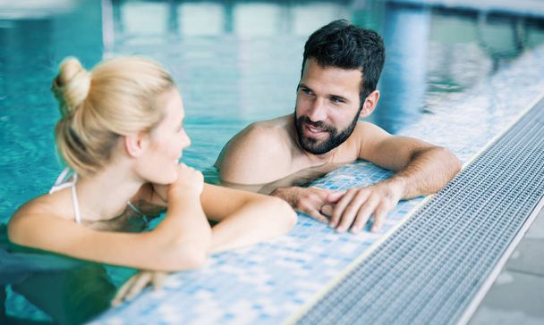 Happy attractive couple relaxing in spa swimming pool - Foto, afbeelding