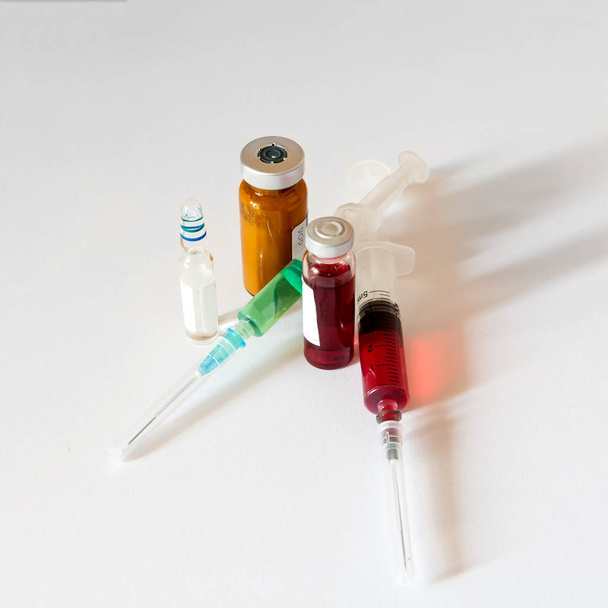 frasco de vidrio médico, ampolla, jeringa médica de plástico llena de medicina roja y verde, sobre fondo blanco
 - Foto, Imagen