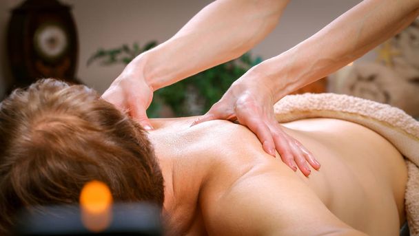 Jovem recebendo massagem no ombro e nas costas do terapeuta no spa
 - Foto, Imagem