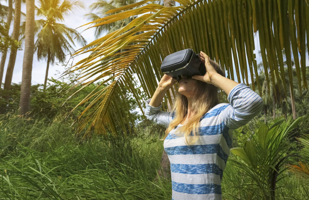 Virtuele realiteit Vr 3d headset en vrouw verkennen van het spel op een achtergrond van aard jungle - Foto, afbeelding