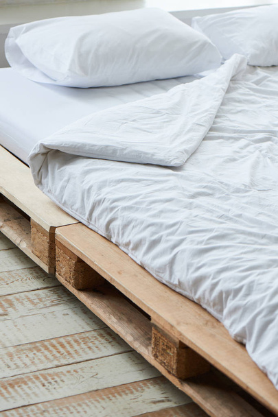 white pillows on wooden bed of pallets, close-up  - Fotó, kép