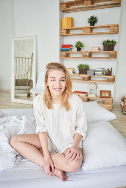 happy attractive woman sitting on bed in apartment, wake up concept   - Zdjęcie, obraz