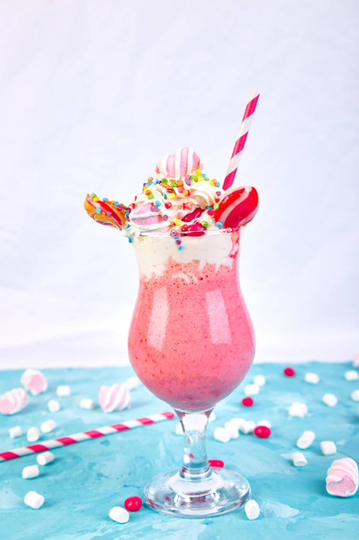 Рожевий екстремальний молочний коктейль з ягодою, розмарином, полуницею, цукерками зефір, льодяниками на синьому фоні. Копіювати простір. Тенденція харчування
 - Фото, зображення